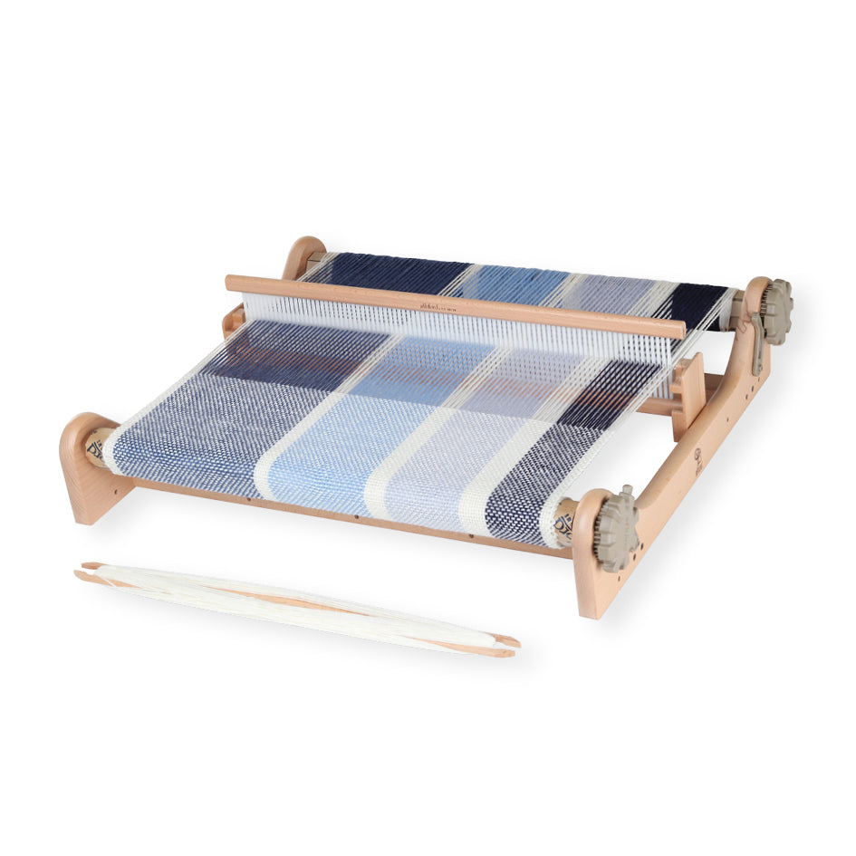 Wooden Ashford Rigid Heddle Loom set up for weaving, showing colorful yarn threaded through the heddle and a woven section of fabric in progress